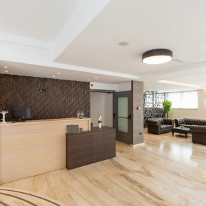 Commercial lobby with reception desk, textured accent wall, and leather lounge seating